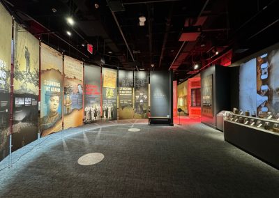 A museum exhibition that shows colorful panels hanging from the ceiling and two spotlights on the floor.