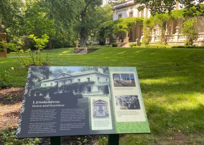 Outdoor signage in front of a historic mansion.