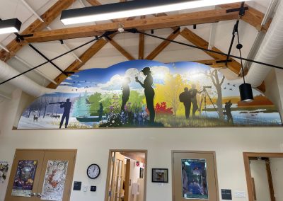 An inset mural in a visitor center that has the silhouettes of people doing things outdoors.