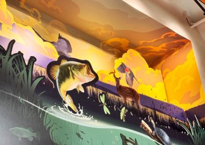 A recessed niche in an educational center that has a mural of fish, deer, and water fowl.