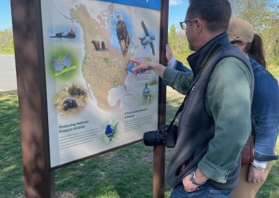 Two people examine a map of the United States on an outdoor sign.