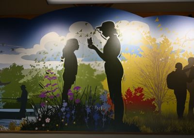 A mural that shows the silhouettes of two people looking at butterflies.
