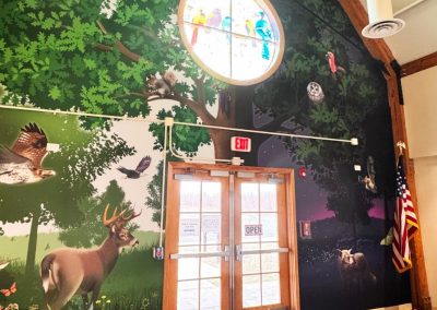 An interior mural that shows animals who live around an oak tree.