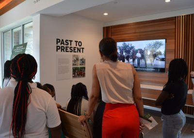 Students crowd around a video monitor in an education center.