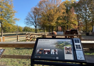 Outdoor signage next to a horse paddock.