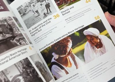 A person flips through a publication that has photos of people in historic clothing.