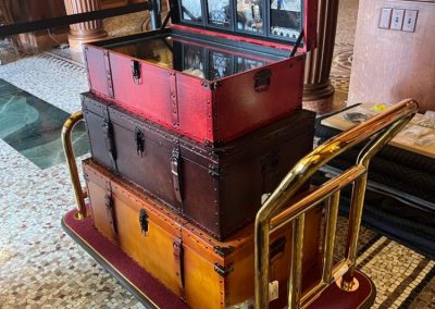 Three antique-looking leather trunks stacked on a wheeled cart