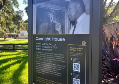 An outdoor sign with text, images, and QR codes that has a picture of Martin Luther King.