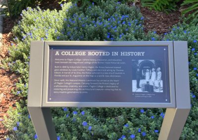 A metal outdoor sign that talks about the history of Flagler College.