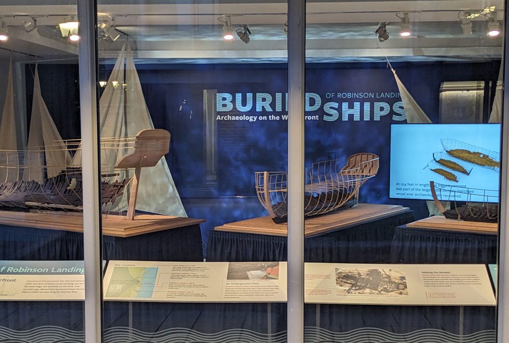 A window front that shows off a reader rail, model ships, and a backdrop that says, Buried Ships of Alexandria.