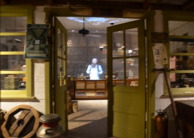 Green doors inside a recreated general store open up to reveal a man standing behind a counter.
