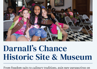 Girl Scouts sit in the lobby of a historic house and pose for a photo.