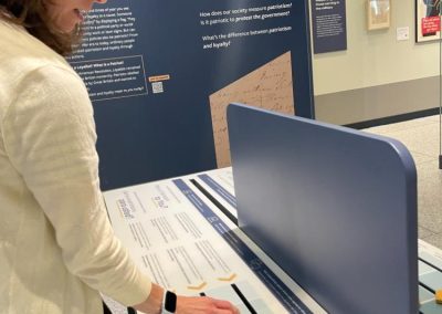 A person with a white shirt moves a yellow slider along an interactive in a museum setting.