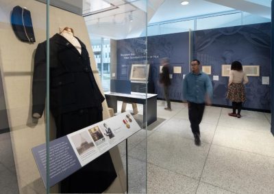 A case inside a museum exhibit contains a black coat from the 20th century.